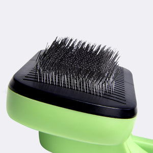 Green and black pet grooming brush on a light gray background