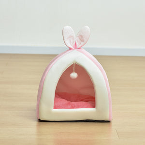 Pink pet bed with bunny ears on a wooden floor