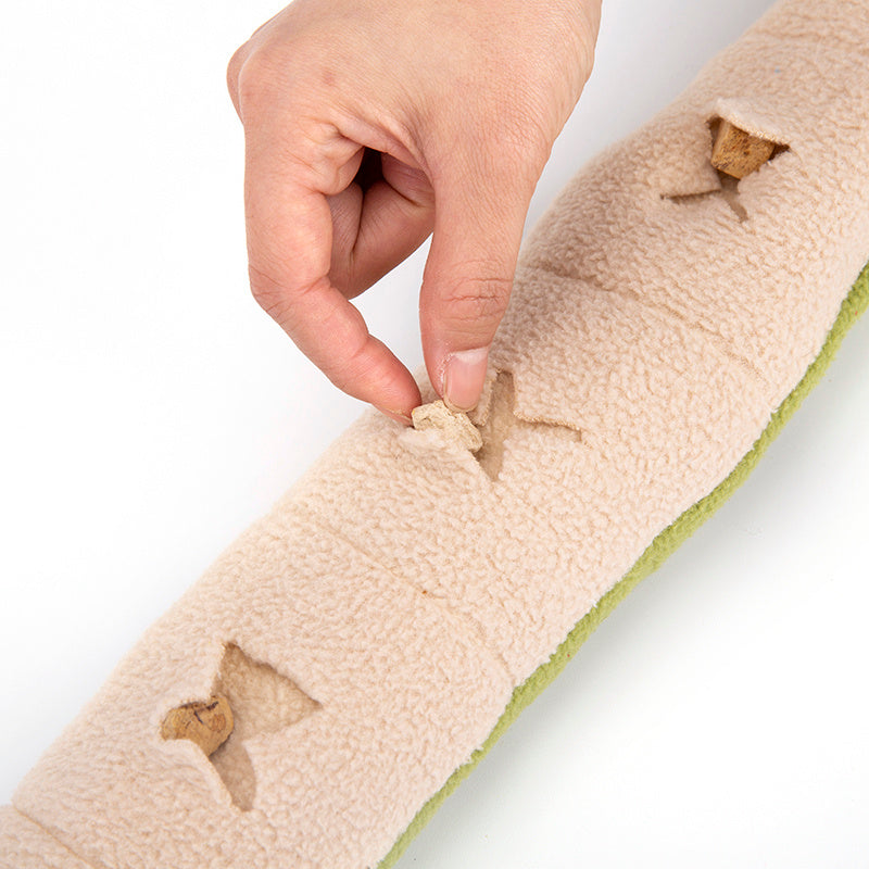 Hand holding a beige fabric strip with embroidered designs on a white background