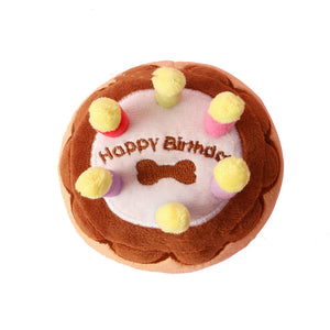 Plush toy shaped like a birthday cake with 'Happy Birthday' text on a white background